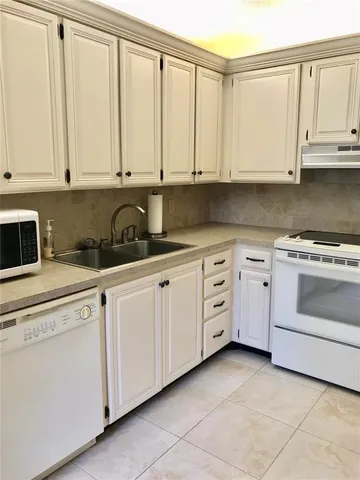 a kitchen with white cabinets and white appliances