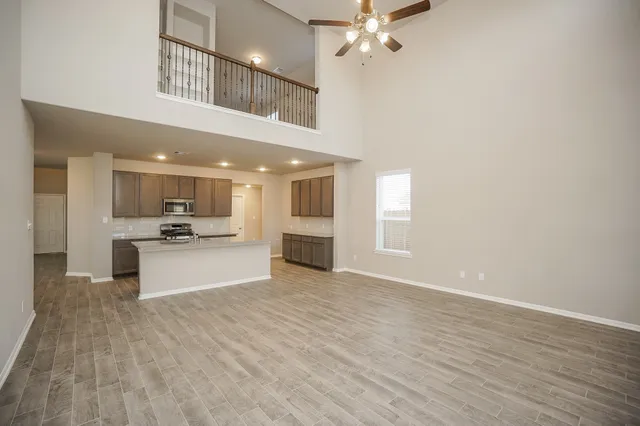 a view of a kitchen with kitchen island a counter top space appliances and a ceiling fan