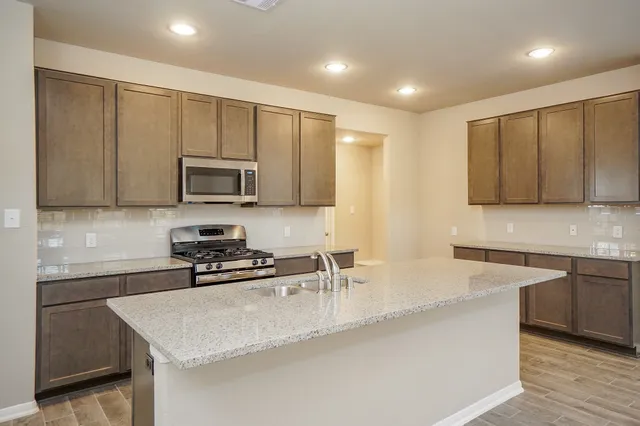 a kitchen with stainless steel appliances granite countertop a sink a stove and a microwave