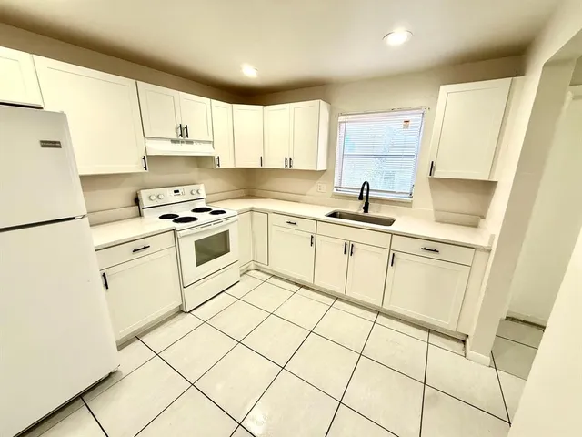 a kitchen with white cabinets appliances and a sink