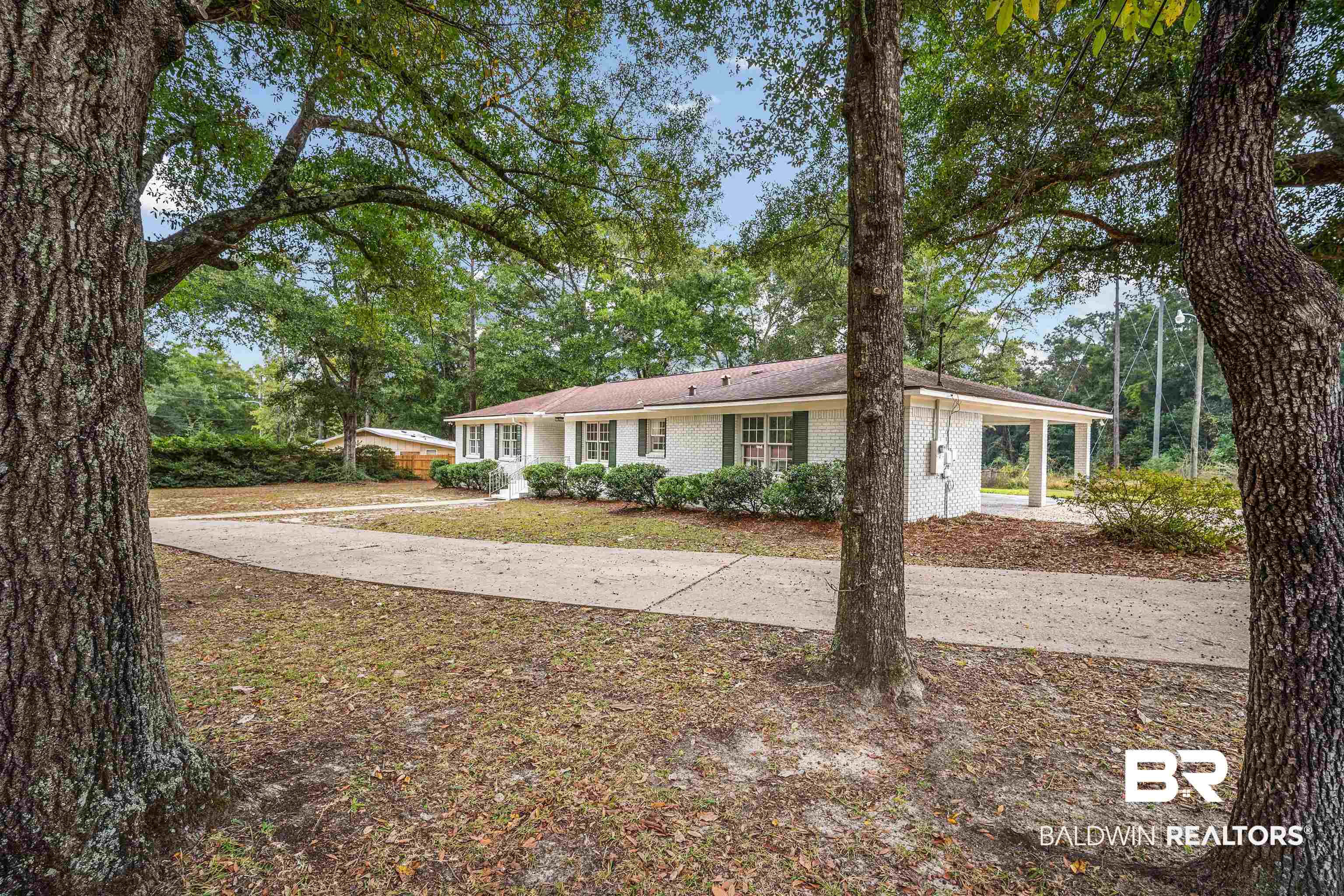 3050 Lacoste Road Mobile, AL 36618 - Photo 2 of 30 Ranch-style home with an attached carport, brick siding, and view of wooded area