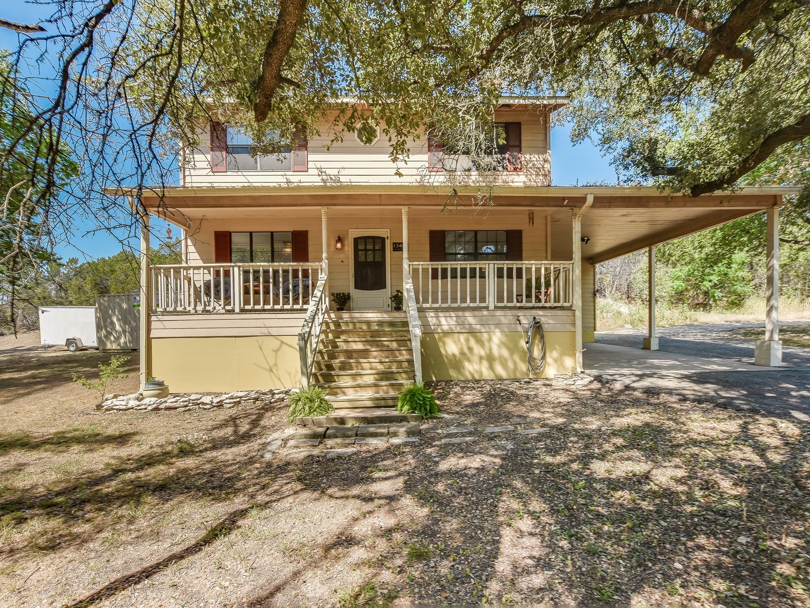 13404 Cedar Lime Road Leander, TX 78641 - Photo 5 of 28 A charming two-story residence with a welcoming front porch and convenient carport, nestled among mature trees.