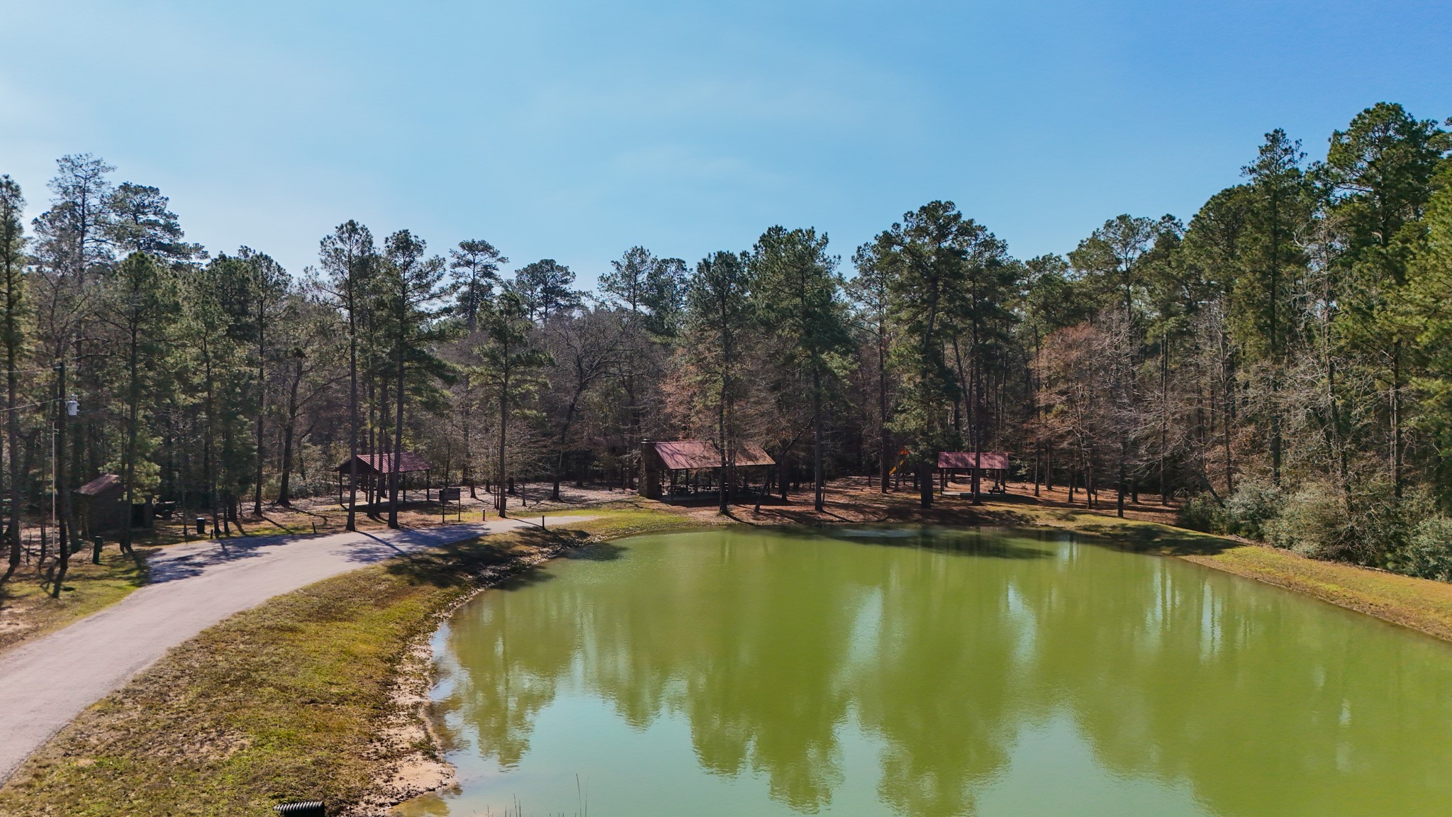5-23-14 Rim Rock Road Huntsville, TX 77340 - Photo 33 of 45 Enjoy the peaceful ambiance of Texas Grand Ranch’s amenities, including this tranquil pond, perfect for relaxation and outdoor activities.