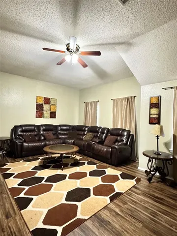 a living room with a black white checkered floor with a gaming machine and wooden floor