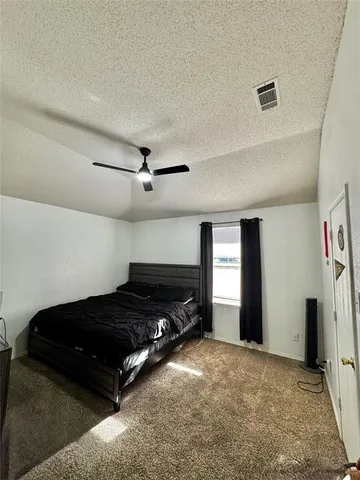 an empty room with a chandelier fan and windows