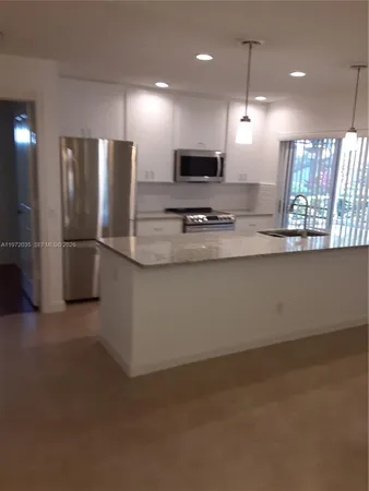 a kitchen with stainless steel appliances granite countertop a refrigerator a sink a stove and a refrigerator