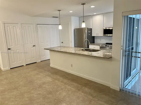 a kitchen with stainless steel appliances granite countertop a refrigerator a oven a sink with white cabinets and a refrigerator