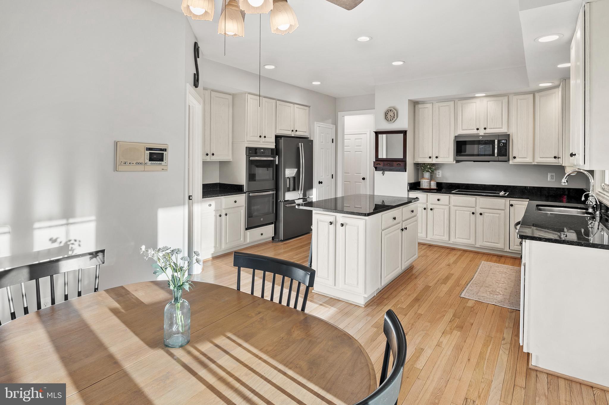 9916 Founders Way Damascus, MD 20872 - Photo 18 of 53 a kitchen with stainless steel appliances granite countertop a refrigerator a stove top oven a sink dishwasher and a dining table with wooden floor