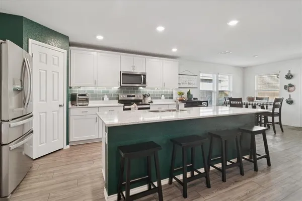 a kitchen with stainless steel appliances a table chairs refrigerator and a sink