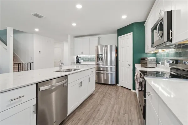 a kitchen with white cabinets sink and stainless steel appliances
