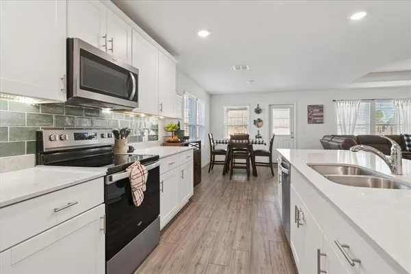 a kitchen with granite countertop a sink wooden floor and stainless steel appliances