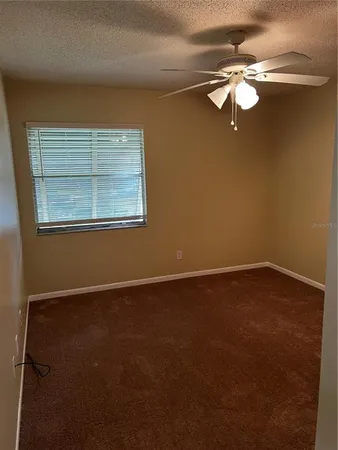 an empty room with a chandelier fan and windows
