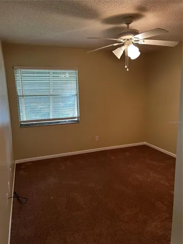 an empty room with a chandelier fan and windows