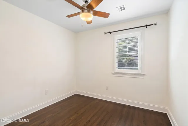 an empty room with a window and a fan