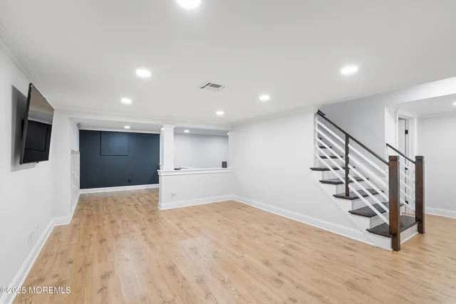 a view of an empty room with wooden floor and stairs