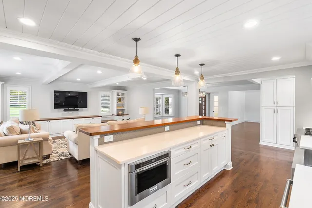 a large white kitchen with a large island oven a sink and stainless steel appliances