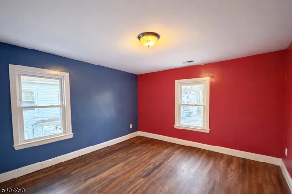 a view of empty room with window and wooden floor