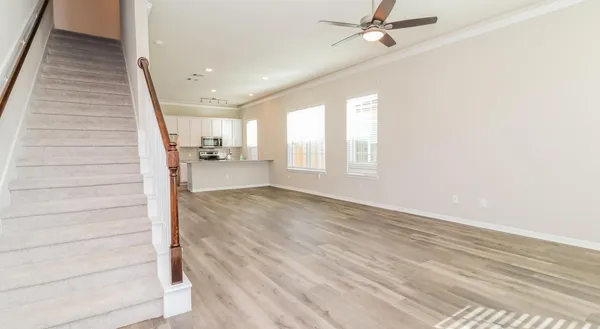 a view of a hallway to a room with wooden floor and staircase