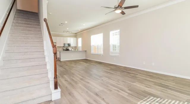 a view of a hallway to a room with wooden floor and staircase