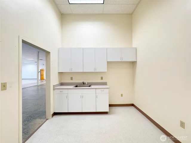 a view of an empty room with kitchen appliances and a chandelier