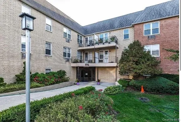 a view of a house with brick walls and a yard with plants