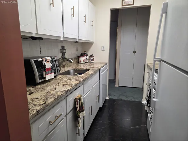 a kitchen with stainless steel appliances granite countertop a refrigerator a stove and a sink