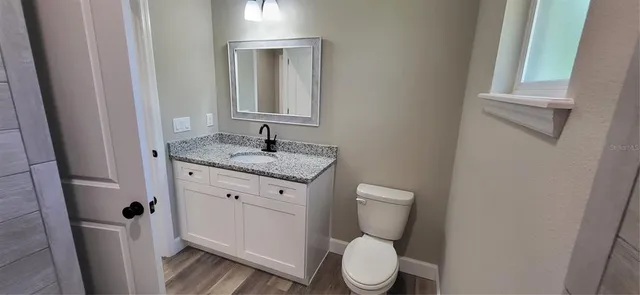 a bathroom with a granite countertop toilet and a sink