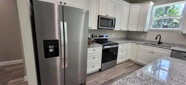 a kitchen with stainless steel appliances granite countertop a refrigerator sink and stove