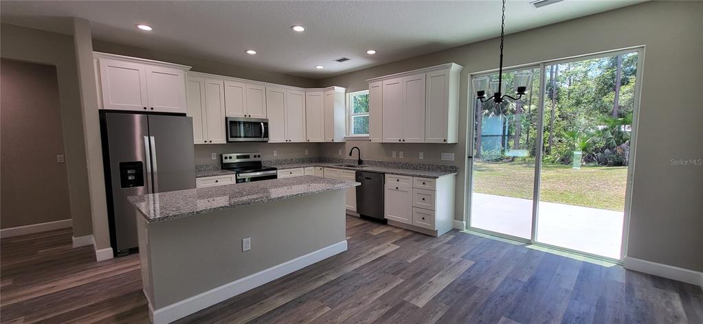 1666 Berrybush Street Bunnell, FL 32110 - Photo 9 of 26 a kitchen with stainless steel appliances granite countertop a refrigerator a sink dishwasher a stove and white countertops with wooden floor
