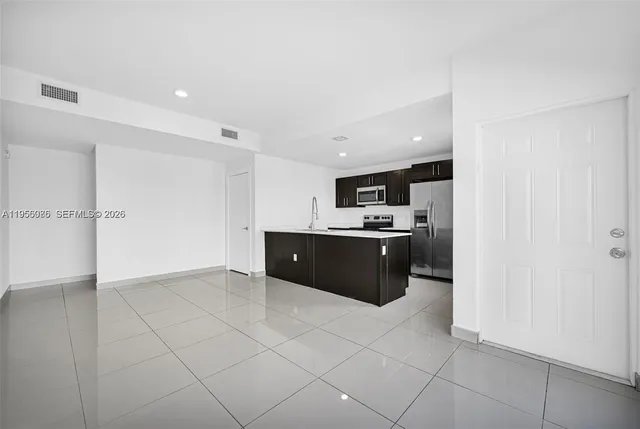 a view of kitchen with cabinets and refrigerator