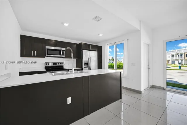 a kitchen with stainless steel appliances a sink a stove a microwave a sink a refrigerator and grey cabinets