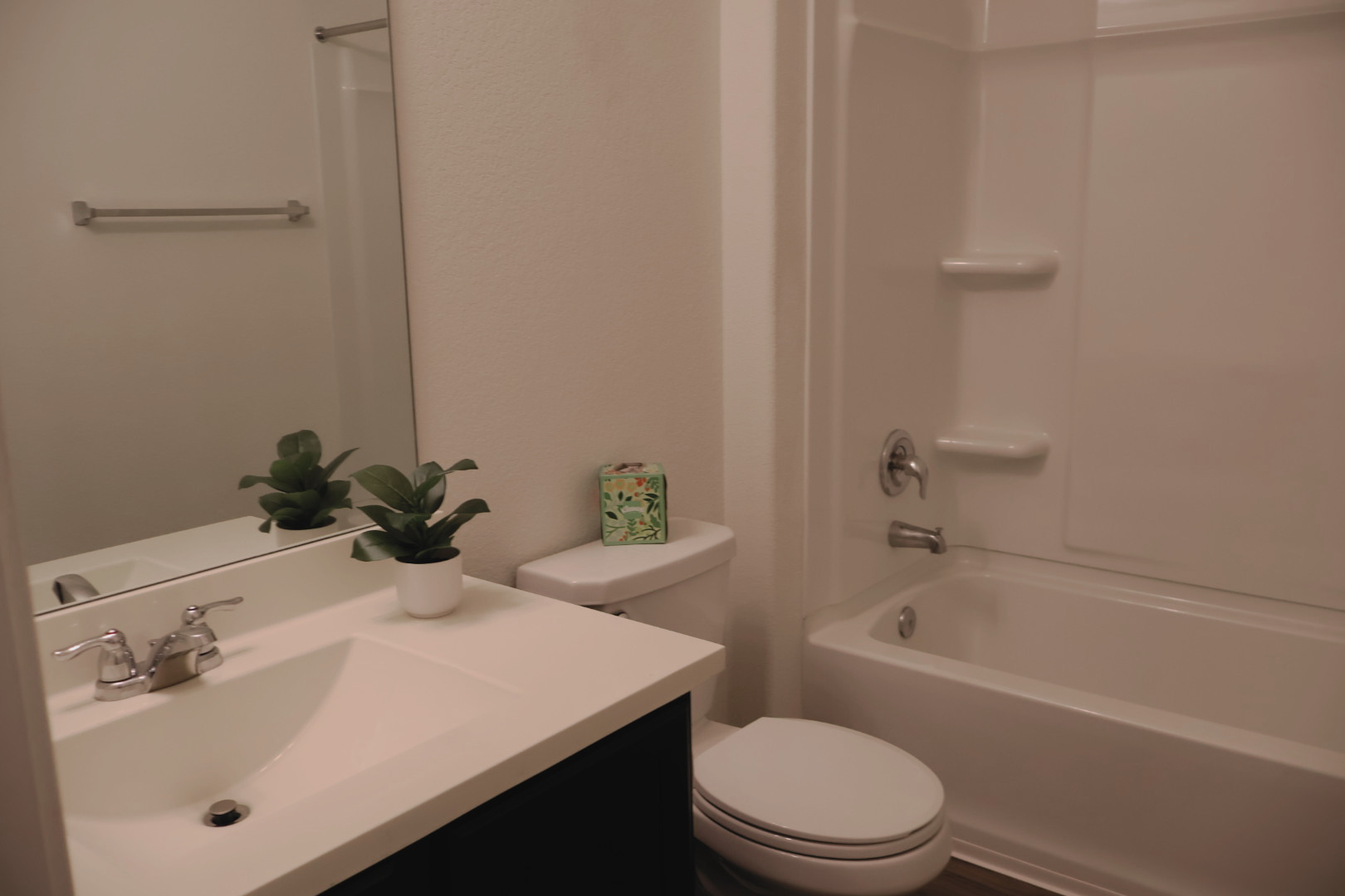 117 Galaxy Way Jarrell, TX 76537 - Photo 15 of 17 White bathroom featuring a built-in tub and shower unit , a sleek toilet, and a vanity with an integrated sink and chrome faucet