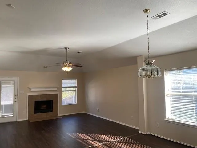 a view of an empty room with wooden floor fireplace and a window