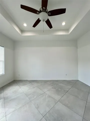 an empty room with a ceiling fan and window