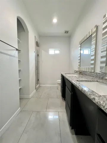 a bathroom with a granite countertop sink a toilet and a mirror