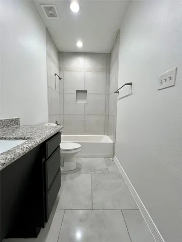 a bathroom with a granite countertop sink a toilet and shower