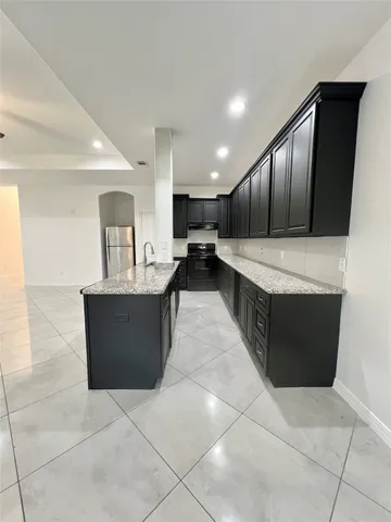 a large kitchen with kitchen island a sink a counter and wooden cabinets