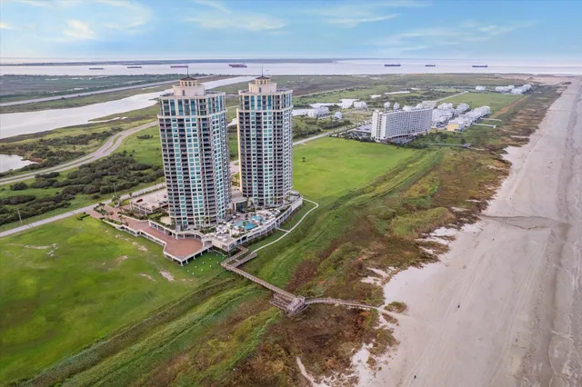 a living room with stainless steel appliances furniture a rug and a kitchen view