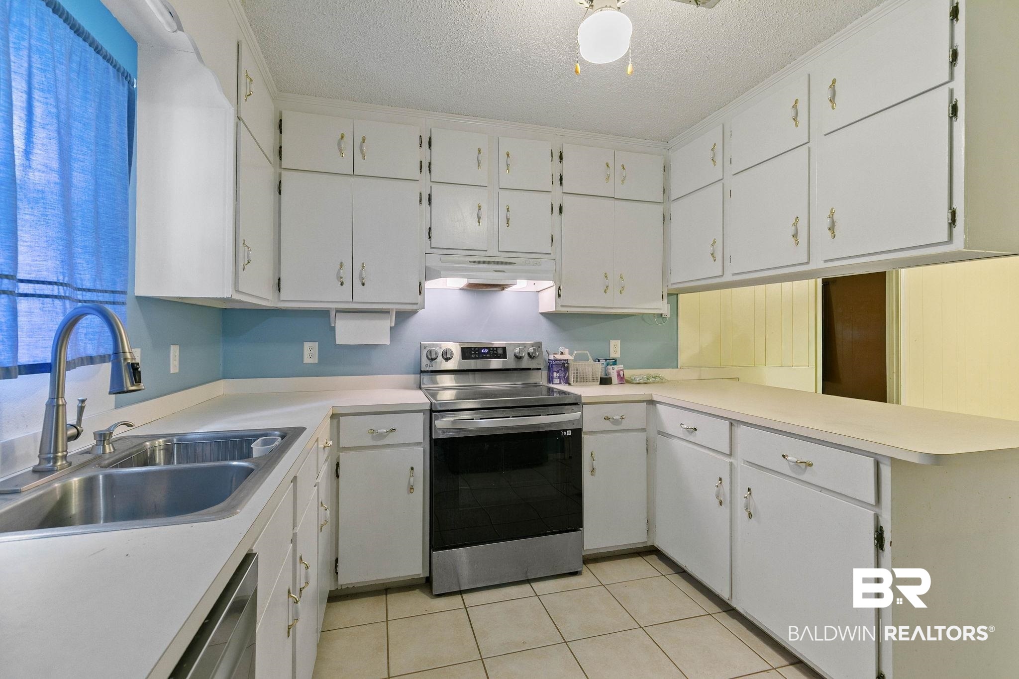 13653 Roberts Road Loxley, AL 36551 - Photo 13 of 33 Kitchen featuring a double basin stainless steel sink with a high-arc faucet, white cabinetry, light countertops, and a full suite of stainless steel appliances