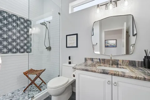 a bathroom with a granite countertop toilet sink and mirror