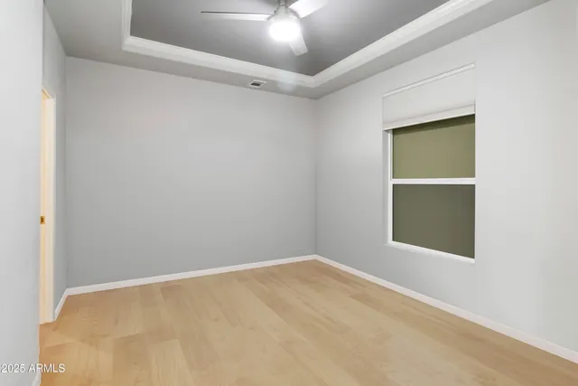 an empty room with a chandelier fan and windows