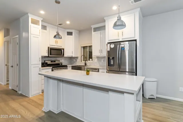 a kitchen with stainless steel appliances a sink stove refrigerator and cabinets
