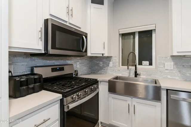 a kitchen with stainless steel appliances granite countertop a sink stove and microwave