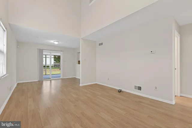 a view of an empty room with wooden floor and window