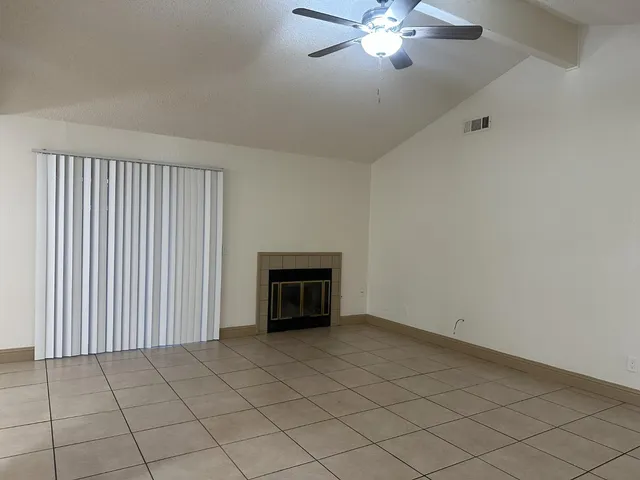 a view of an empty room with a fireplace and a chandelier fan