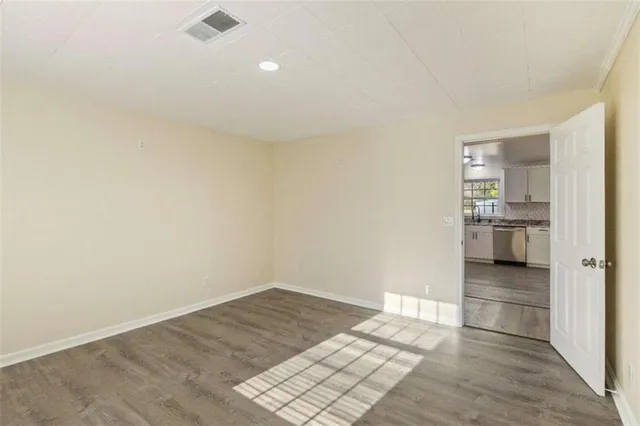 an empty room with wooden floor ceiling fan and windows