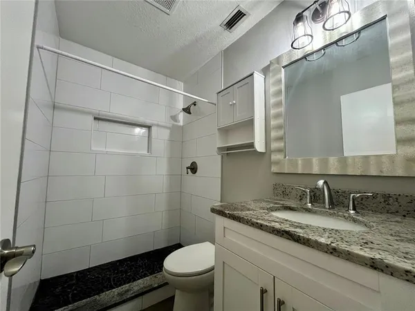 a bathroom with a granite countertop sink toilet and shower
