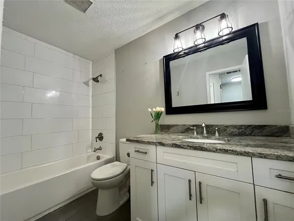 a bathroom with a toilet sink vanity tub and shower