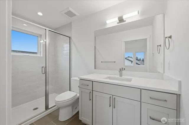 a bathroom with a toilet sink vanity and shower