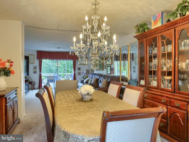 a view of a dining room with furniture a chandelier and large windows